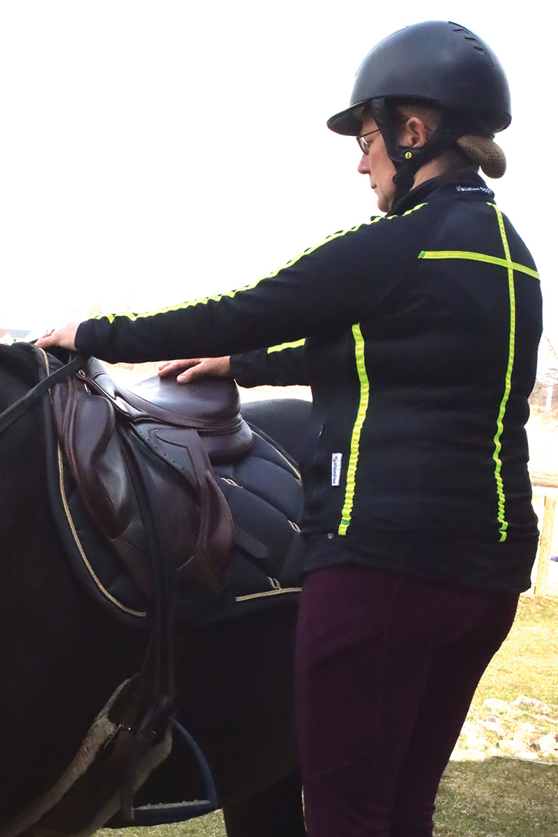 An equestrian assesses her breathing before mounting