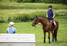 A rider listens to her riding coach while aboard her horse