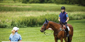 A rider listens to her riding coach while aboard her horse