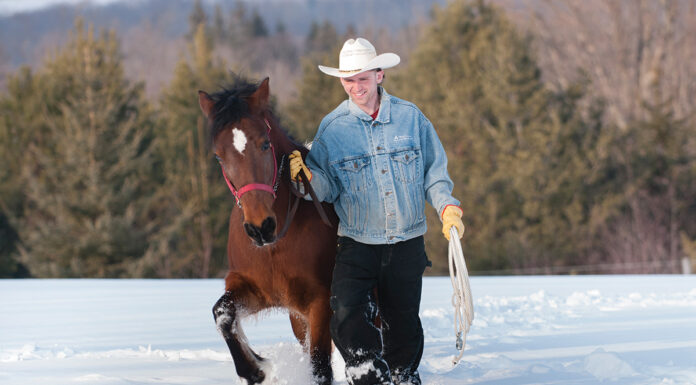 A man leads a horse through deep snow.