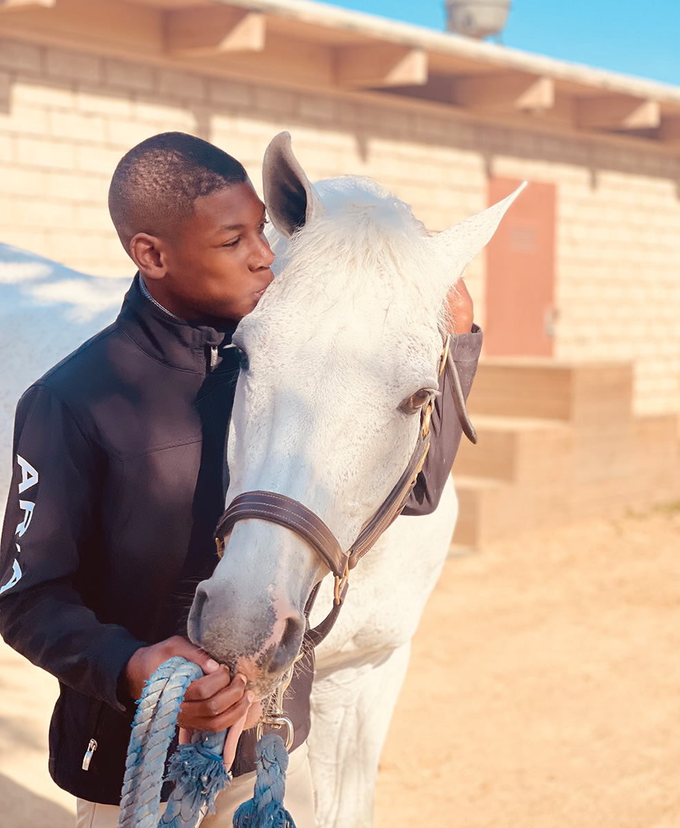 A young boy kisses a horse. This equine therapy has helped him with his ADHD.