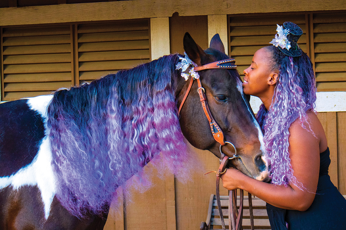 A Paint mare and woman both adorned in purple share a kind moment