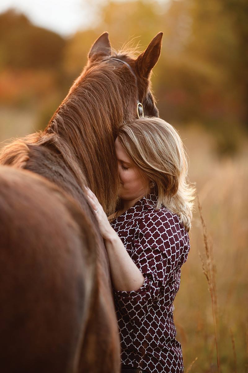 A woman hugs her chestnut gelding