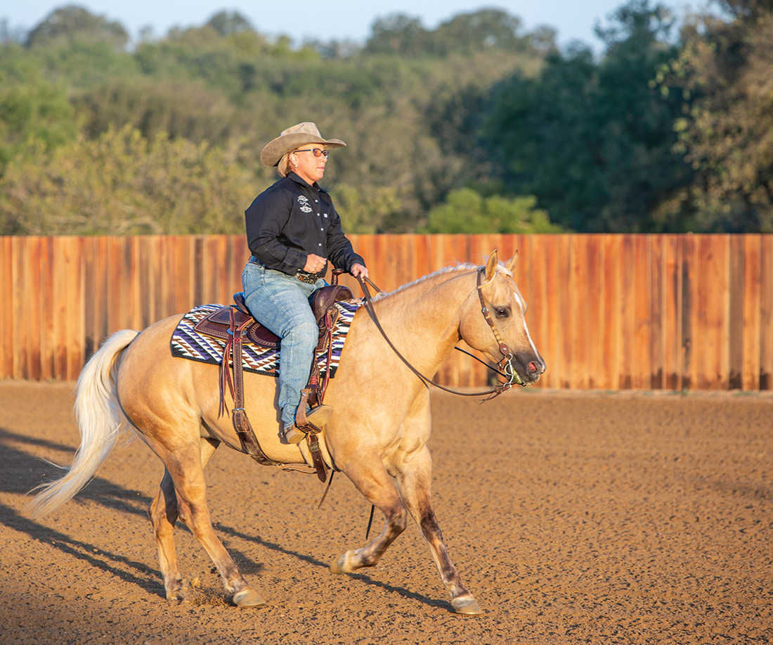 Shannon Pigott, a riding coach, loping a palomino horse