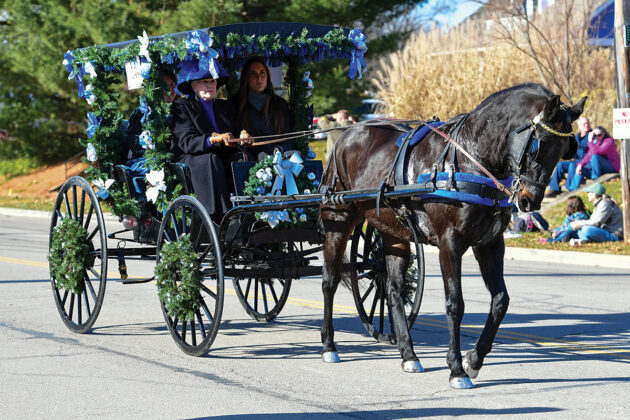 A black horse pulls a decorated carriage Lebanon Horse-Drawn Carriage Parade and Christmas Festival.