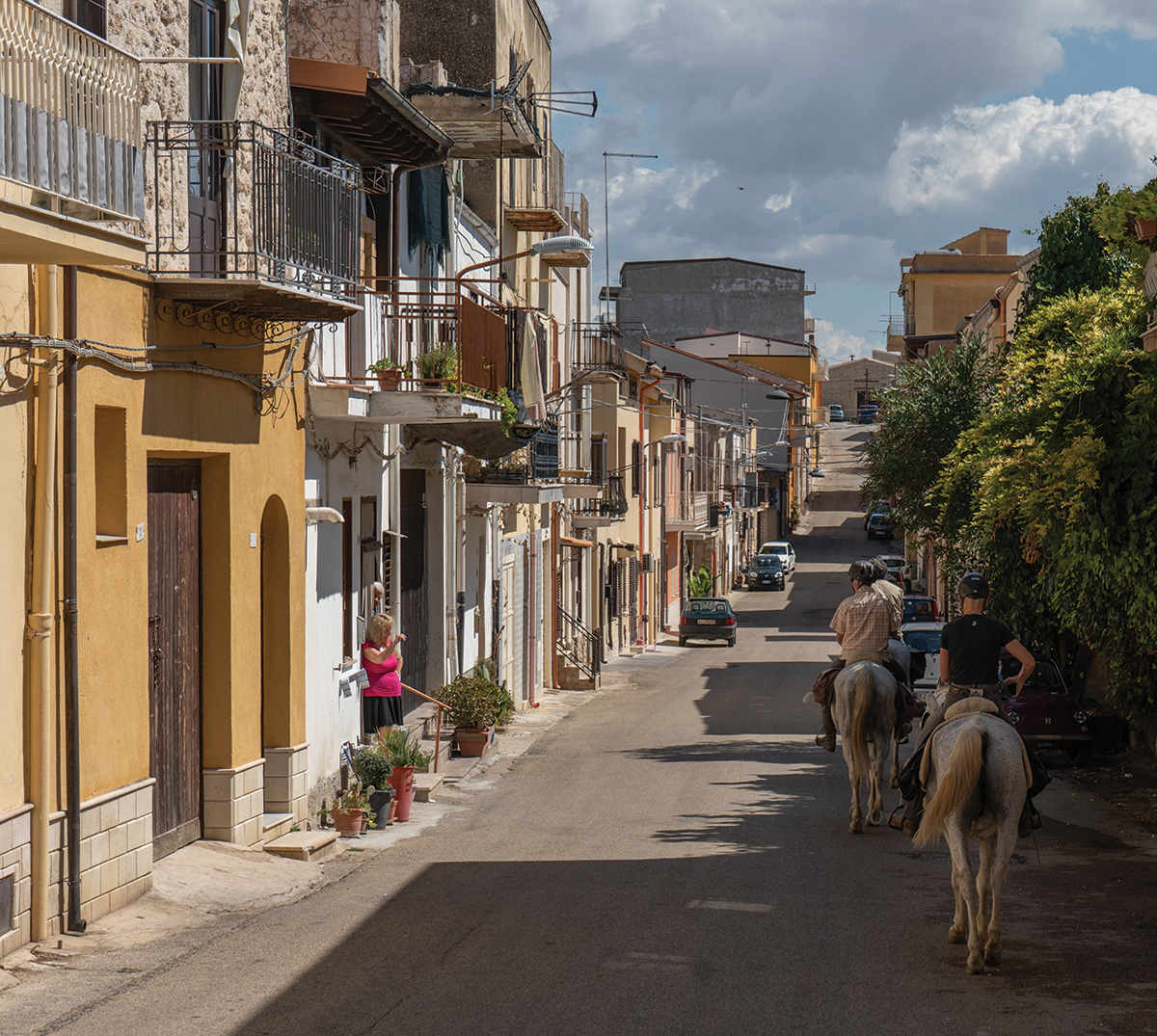 Horseback riders riding through a Sicily village